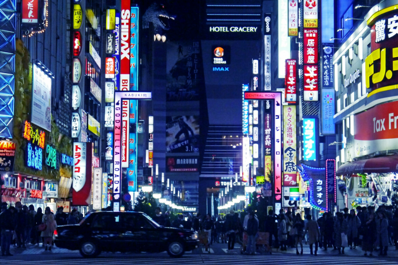 夜の東京の風景。たくさんの人と光る無数の看板が見える。東京・歌舞伎町