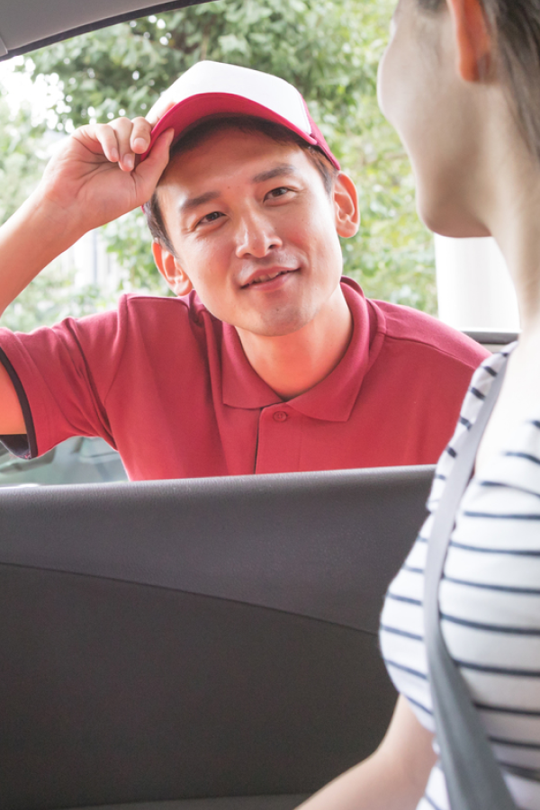 ガソリンスタンドでスタッフが車に乗った女性へ接客している様子