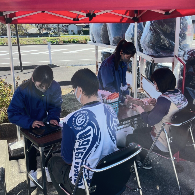 ガソリンスタンドのイベントブースで、商品の申込受付をしている様子