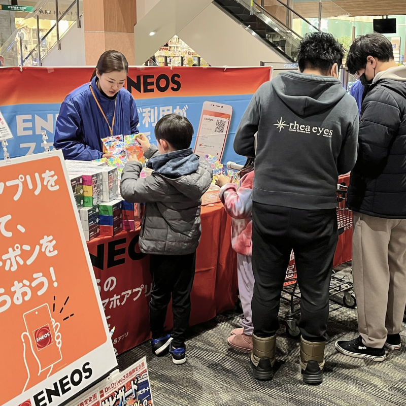 イベントでスタッフが子どもに景品を渡しており、その隣ではスタッフがお客様にアンケートを取っている様子